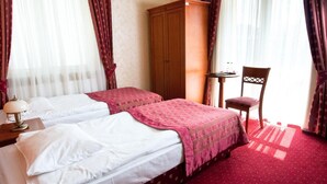 Habitació d'hotel amb dos llits, un armari de fusta, una taula petita i una cadira.