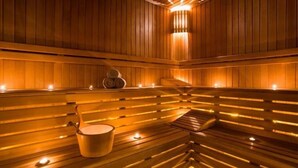 Sauna de fusta amb seients i una làmpada central.