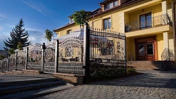 A two-story building with a gated entrance, a balcony with decorative railings, and a red-tiled roof.