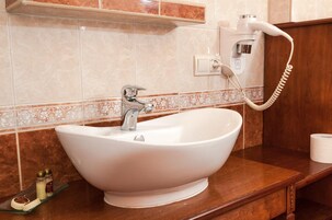 Un baño con lavamanos blanco, dispensador de toallas y teléfono.