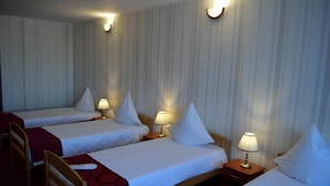 Habitación de hotel con dos camas individuales, cada una con mesita de noche y lámpara, además de una silla de madera.