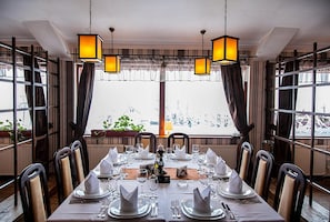 Comedor con mesa dispuesta para cuatro, ventanas amplias y faroles colgantes.
