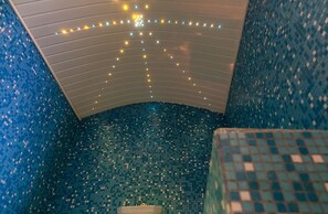 A bathroom with a curved ceiling and blue mosaic tiles.