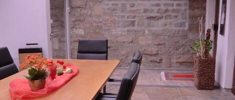 Une salle de conférence avec une longue table, des chaises noires, un mur en pierre et un plafond en verre.