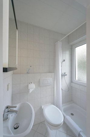 A bathroom with a bathtub, toilet, and sink. - Appart International Boarding House (Würzburg)