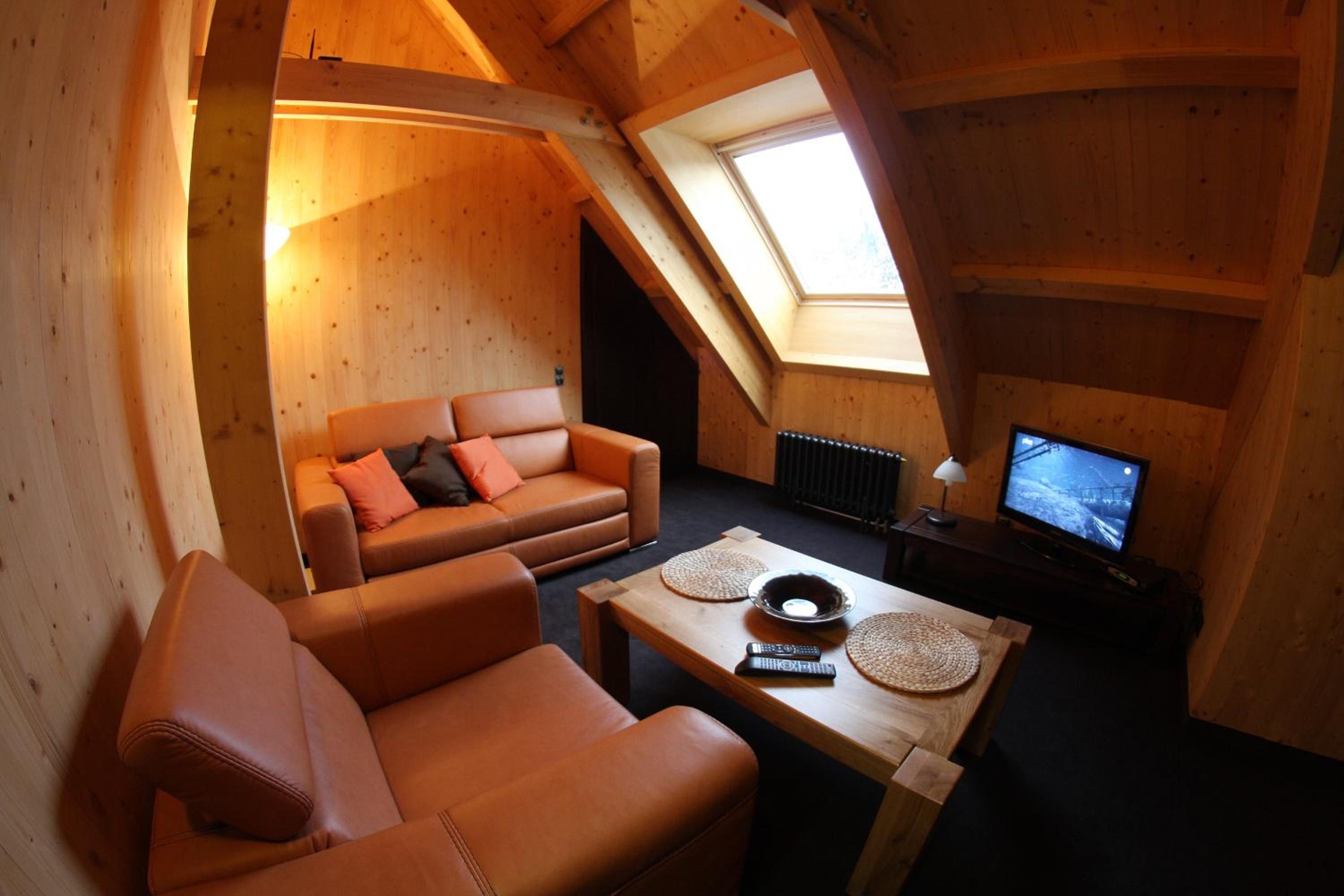 A cozy loft-style room with a wooden interior, a sofa, a coffee table, and a television.