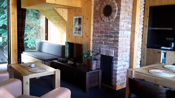 A cozy living room with a fireplace, wooden furniture, and a television.