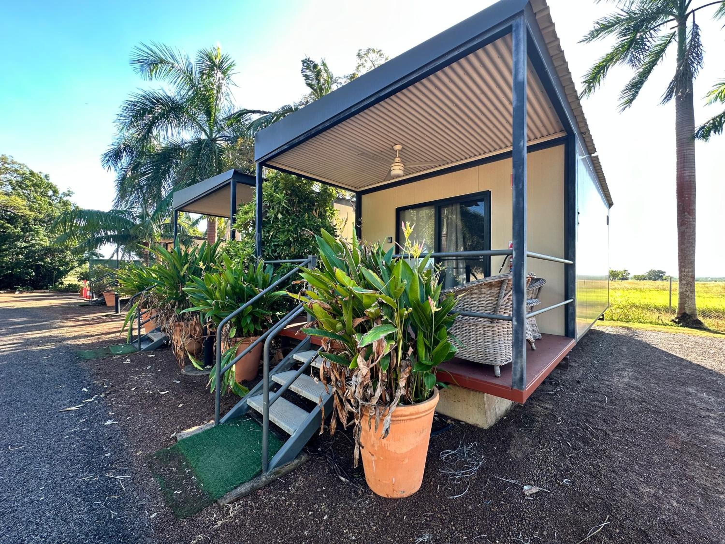 A modern bungalow with a covered porch, a staircase leading to the entrance, and potted plants.