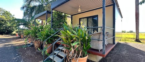 A modern bungalow with a covered porch, a staircase leading to the entrance, and potted plants.