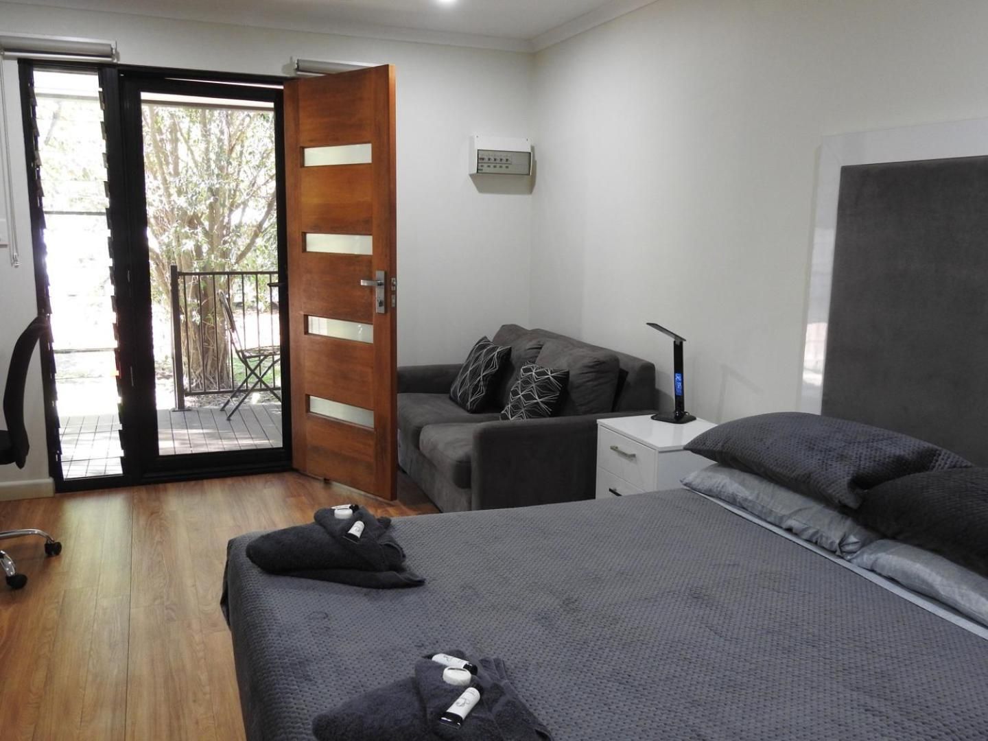 A room with a bed, a desk, a chair, and a door leading to an outdoor area.