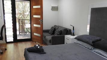 A room with a bed, a desk, a chair, and a door leading to an outdoor area.