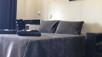 A bedroom with a bed, a desk, a chair, and a painting on the wall.