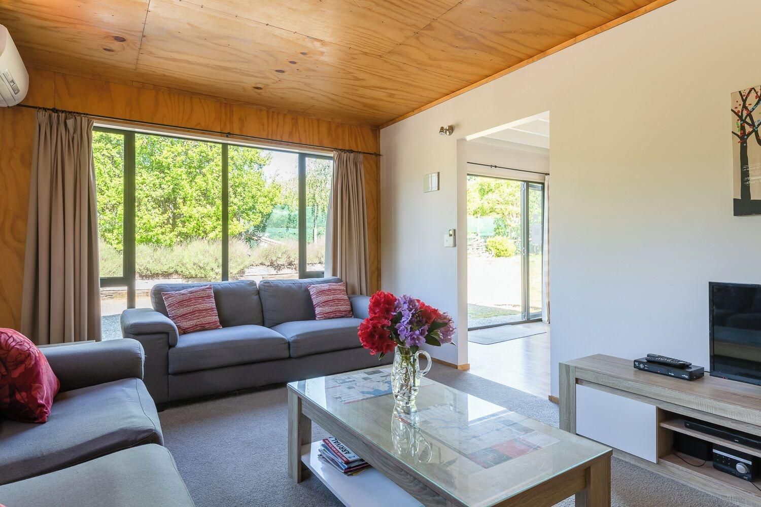 Una sala moderna con un sofá, una mesa de centro con un florero y un televisor.