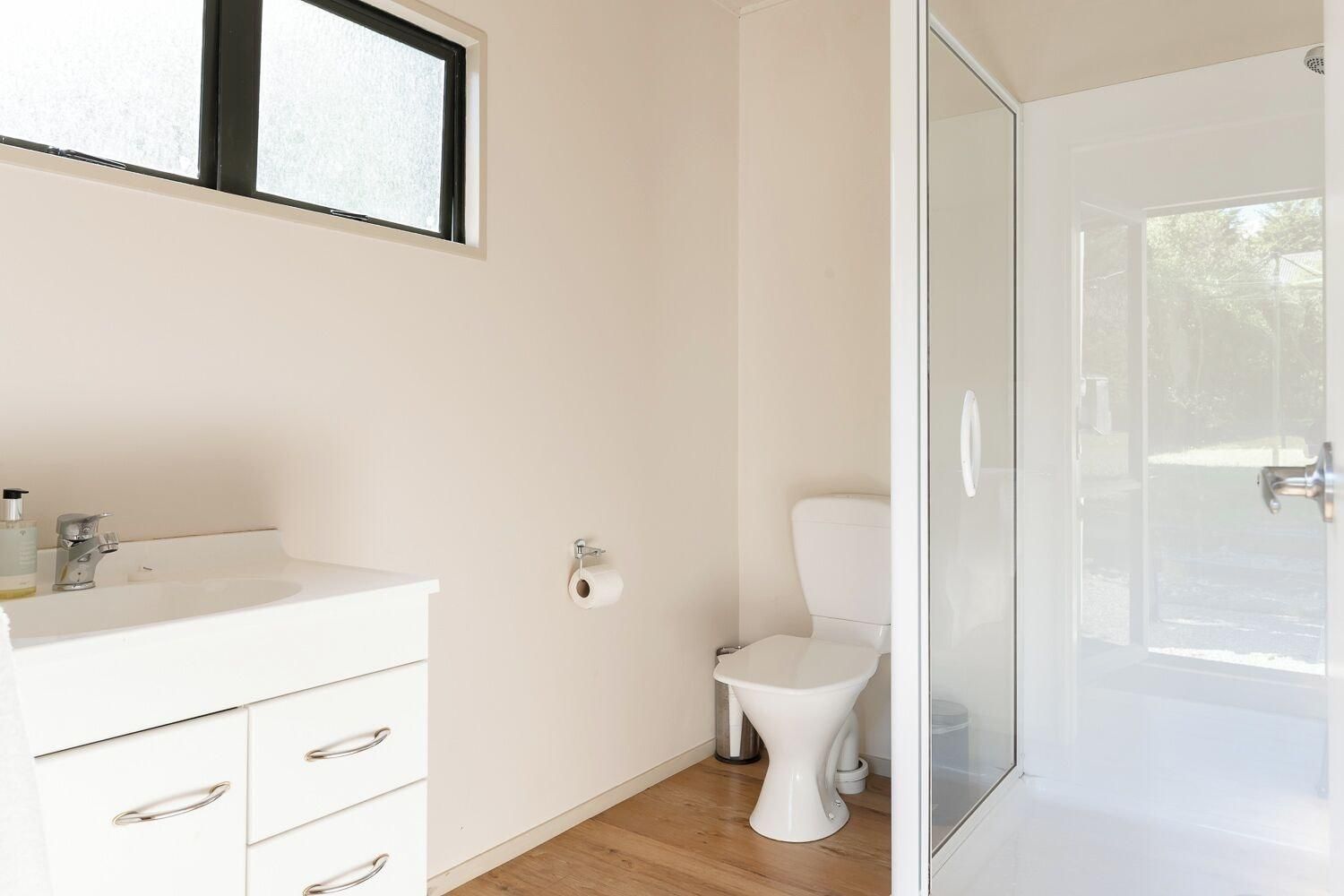 Un baño con lavamanos blanco, inodoro y cabina de ducha de vidrio.