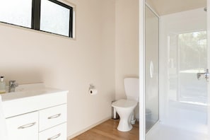 Un baño con lavamanos blanco, inodoro y cabina de ducha de vidrio.