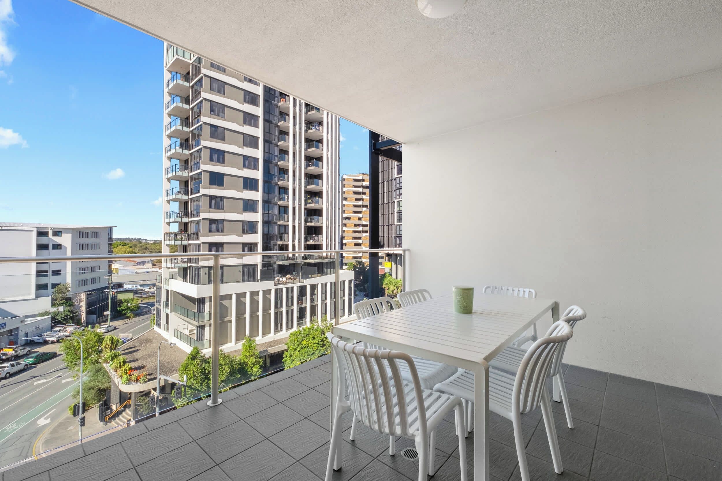Een balkon met een tafel en stoelen, met uitzicht op een stadsbeeld met moderne gebouwen.