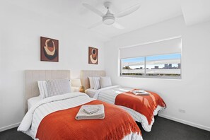 A modern hotel room with two beds, a city view, ceiling fan, and artwork on the wall. - Front Row Convenience - Inner City- 3Bed,2Bath,2Car (Woolloongabba)