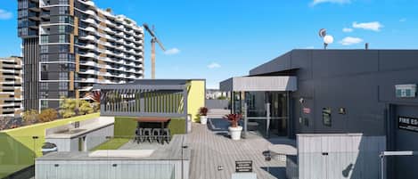 A rooftop pool area with a covered seating area, a pool gate, and a building with a fire safety sign.