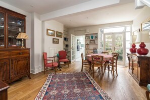 Um quarto espaçoso com um armário de madeira, uma mesa de jantar com cadeiras, um tapete estampado e vista para o exterior através de uma porta de vidro.