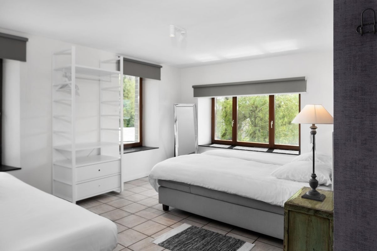 A bedroom with a bed, a wardrobe, a window, and a lamp.