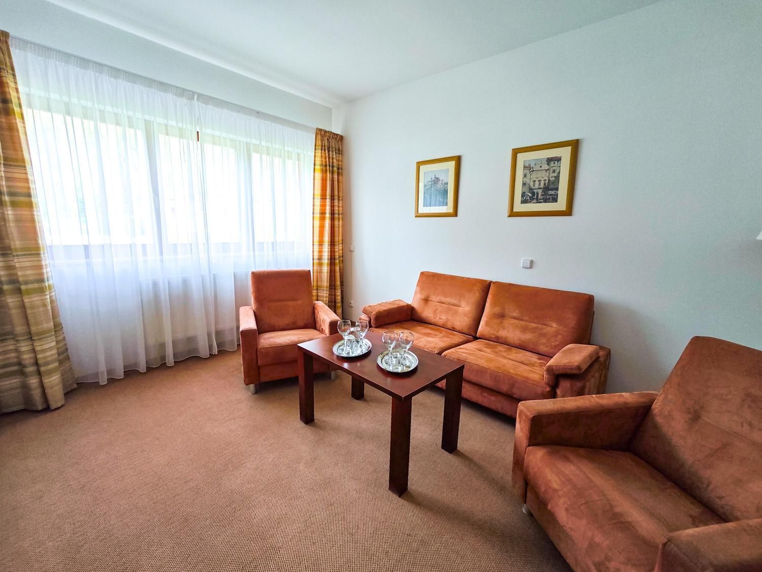 A living room with a sofa, armchairs, a coffee table, and two framed pictures on the wall.