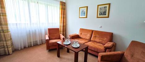 A living room with a sofa, armchairs, a coffee table, and two framed pictures on the wall.