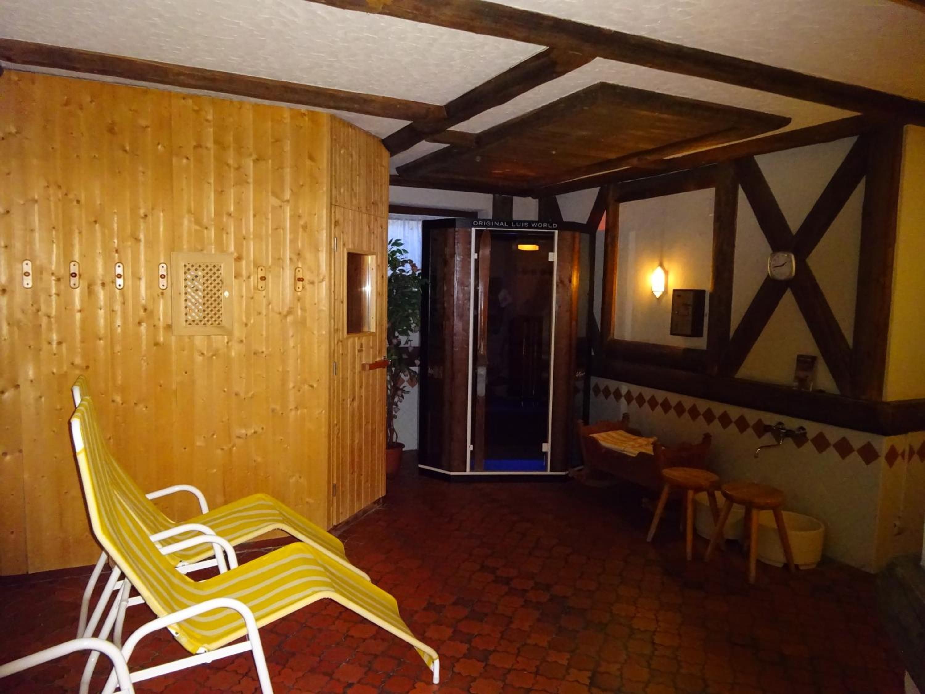 A room with a wooden wall, a door, a yellow striped chair, a small table, and a tiled floor.