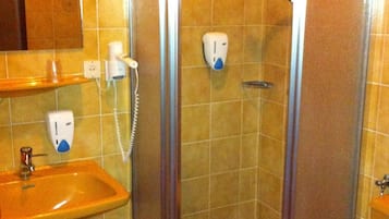 A bathroom with a glass-enclosed shower, a sink, and a toilet.