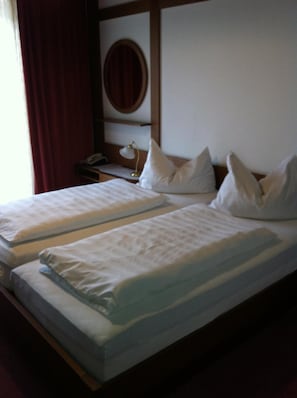 Ett hotellrum med två sängar, ett nattduksbord med en lampa, en spegel och en telefon.