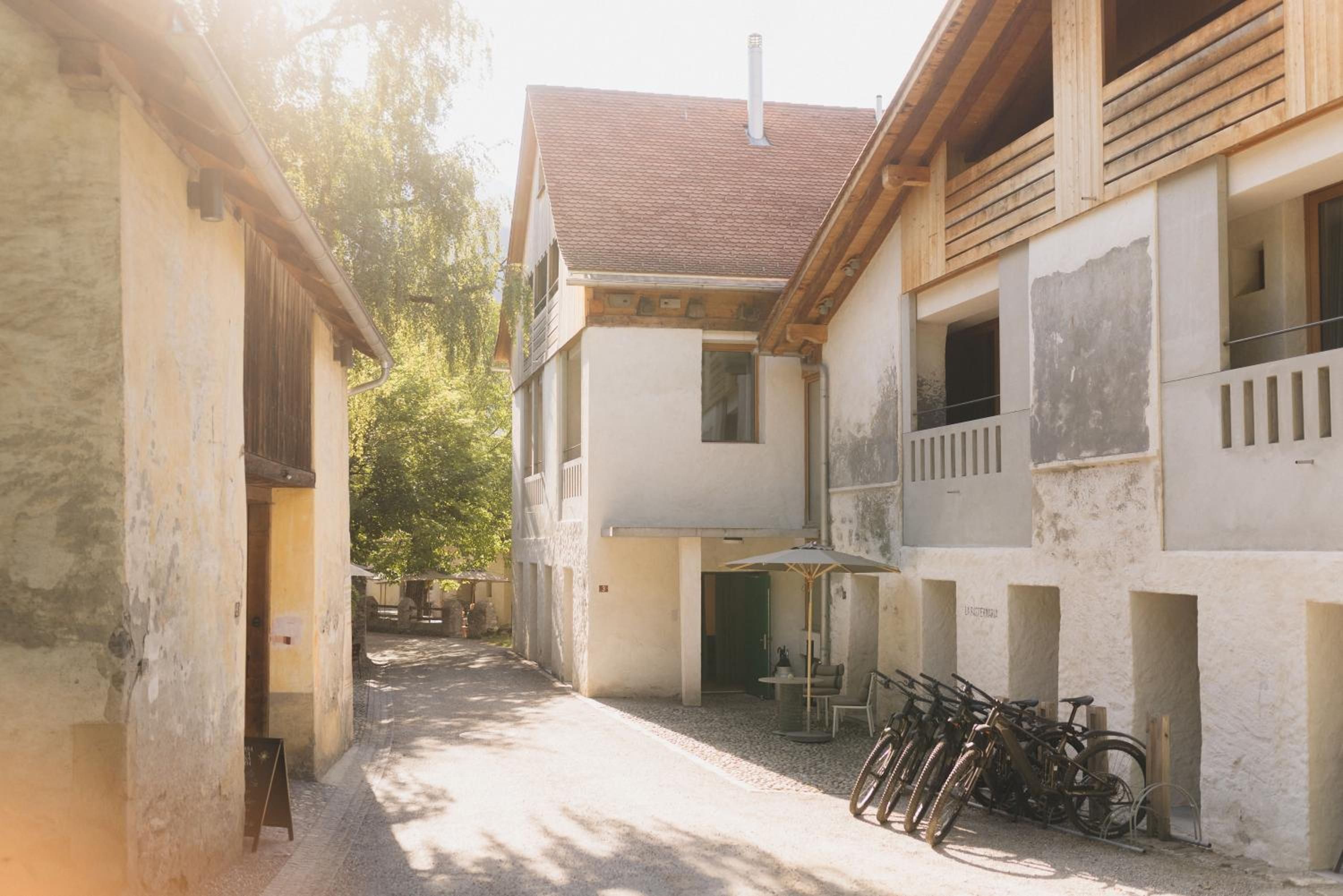 A narrow alleyway between buildings with a bicycle rack and a table with chairs.