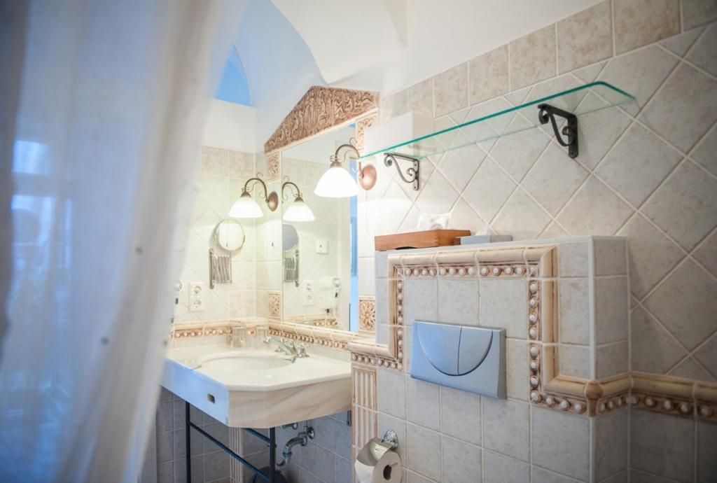 A bathroom with a large mirror, a sink, and a glass shelf.