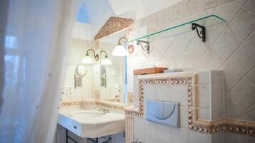 A bathroom with a large mirror, a sink, and a glass shelf.
