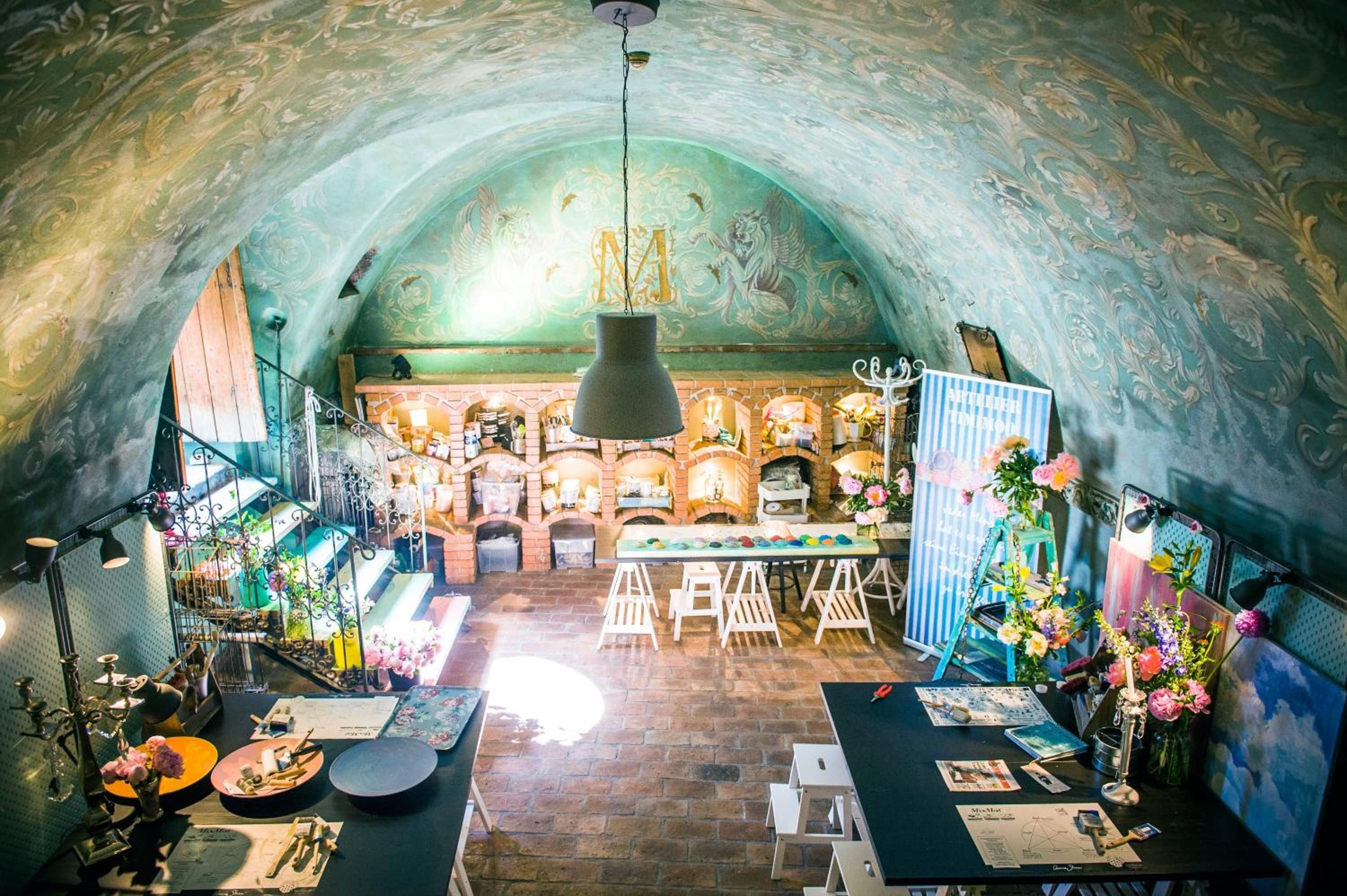 Een interieur met een schouw van baksteen, een hanglamp en een tafel met diverse spullen.