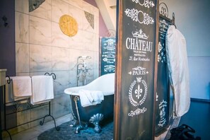 Een badkamer met een vintage badkuip, een handdoekhouder en een decoratieve muur met een rond embleem.