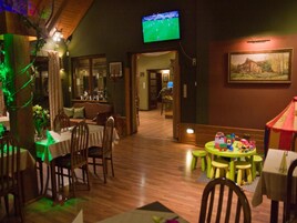 A restaurant with wooden flooring, tables, chairs, a television displaying a soccer game, and a painting on the wall.