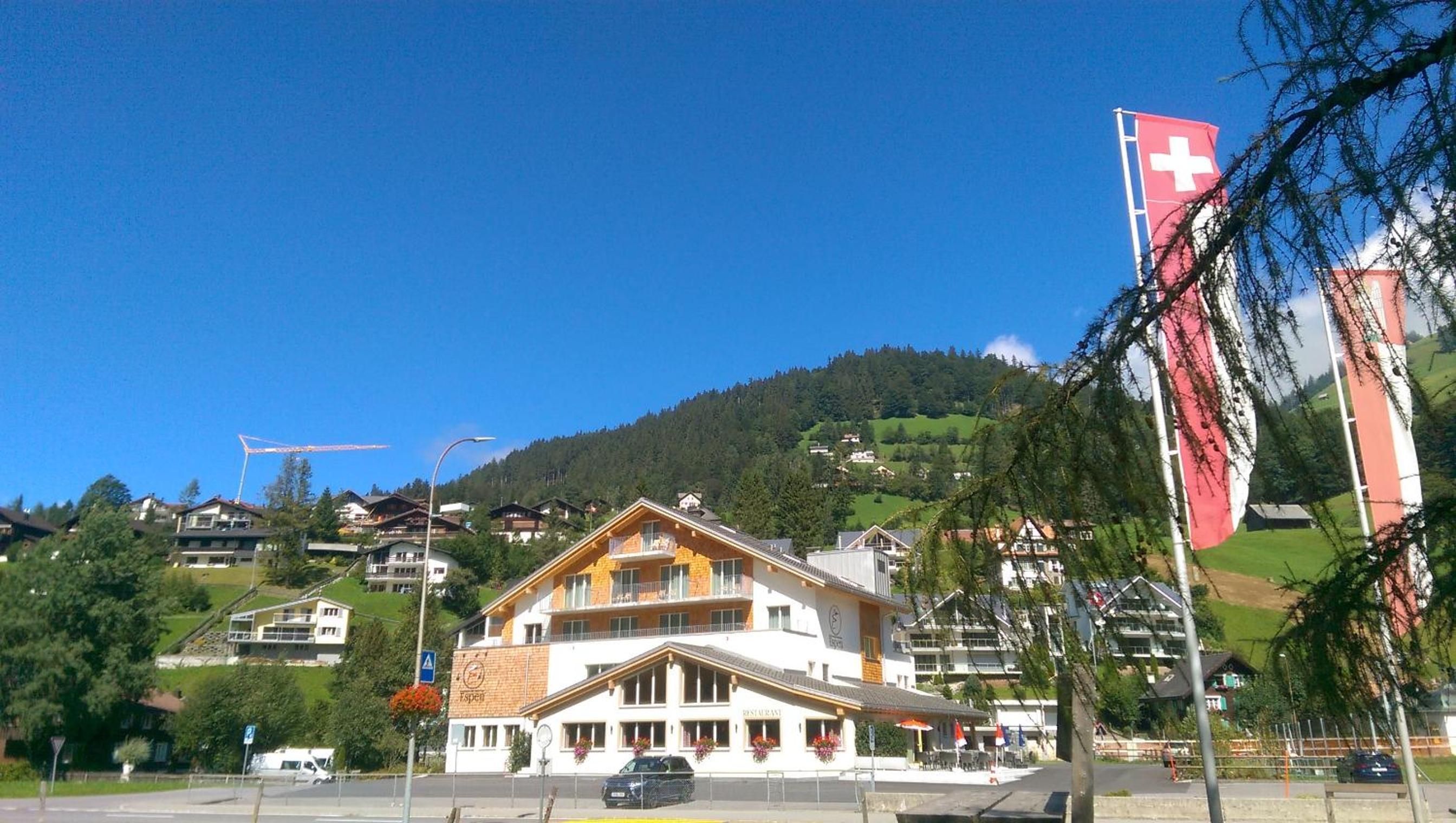 Ein Hotel mit Bergblick, einer roten Flagge und blauem Himmel.