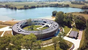 A circular building with a central courtyard, surrounded by a lake and greenery. - Domein Polderwind (Zuienkerke)