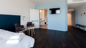A hotel room with a bed, two chairs, a TV, and a bathroom visible through an open door. - Domein Polderwind (Zuienkerke)
