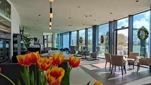 A modern interior with a kitchen area, seating area, and large windows offering views of the outdoors. - Domein Polderwind (Zuienkerke)