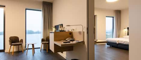 Habitación de hotel con escritorio, dos sillas, cama y vistas al exterior.