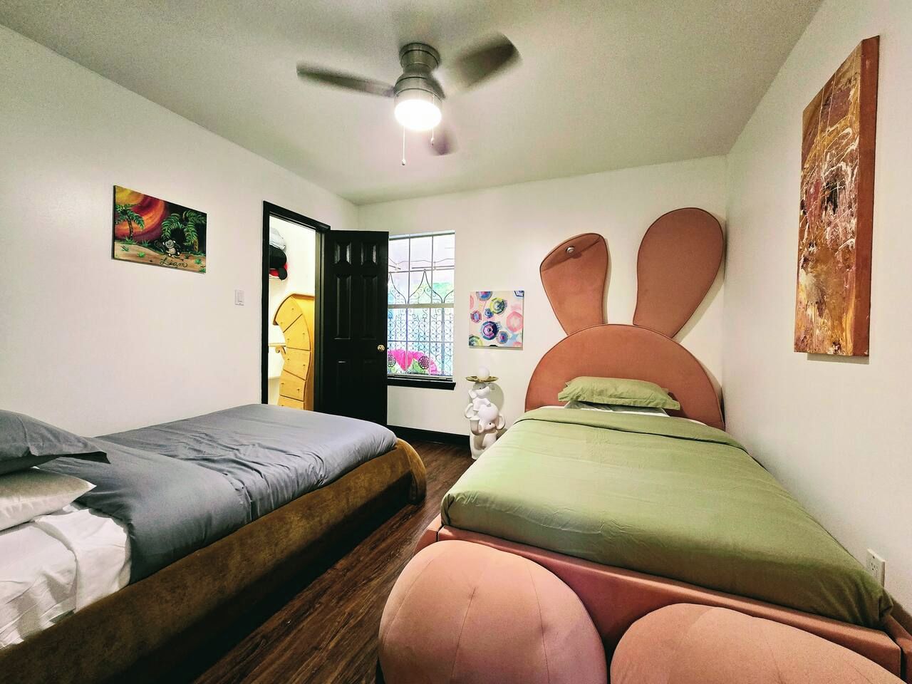 Een slaapkamer met twee bedden, een plafondventilator en een raam met uitzicht.