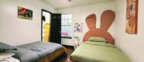 Un dormitorio con dos camas, ventilador de techo y ventana con vistas.