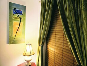 A room with a lamp, a painting, and green curtains. - Casa del Verde - a DZ Collection (Foley)