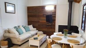 Een woonkamer met een bank, salontafel en een eethoek met stoelen en een tafel.