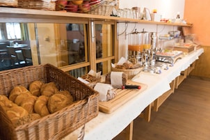 Una mesa de buffet con pan, bollería y bebidas.