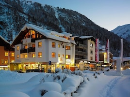 A hotel with multiple buildings, snow-covered surroundings, and a mountainous backdrop.