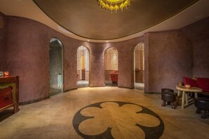 Un vestíbulo con un diseño circular en el suelo, ventanas arqueadas y un candelabro.