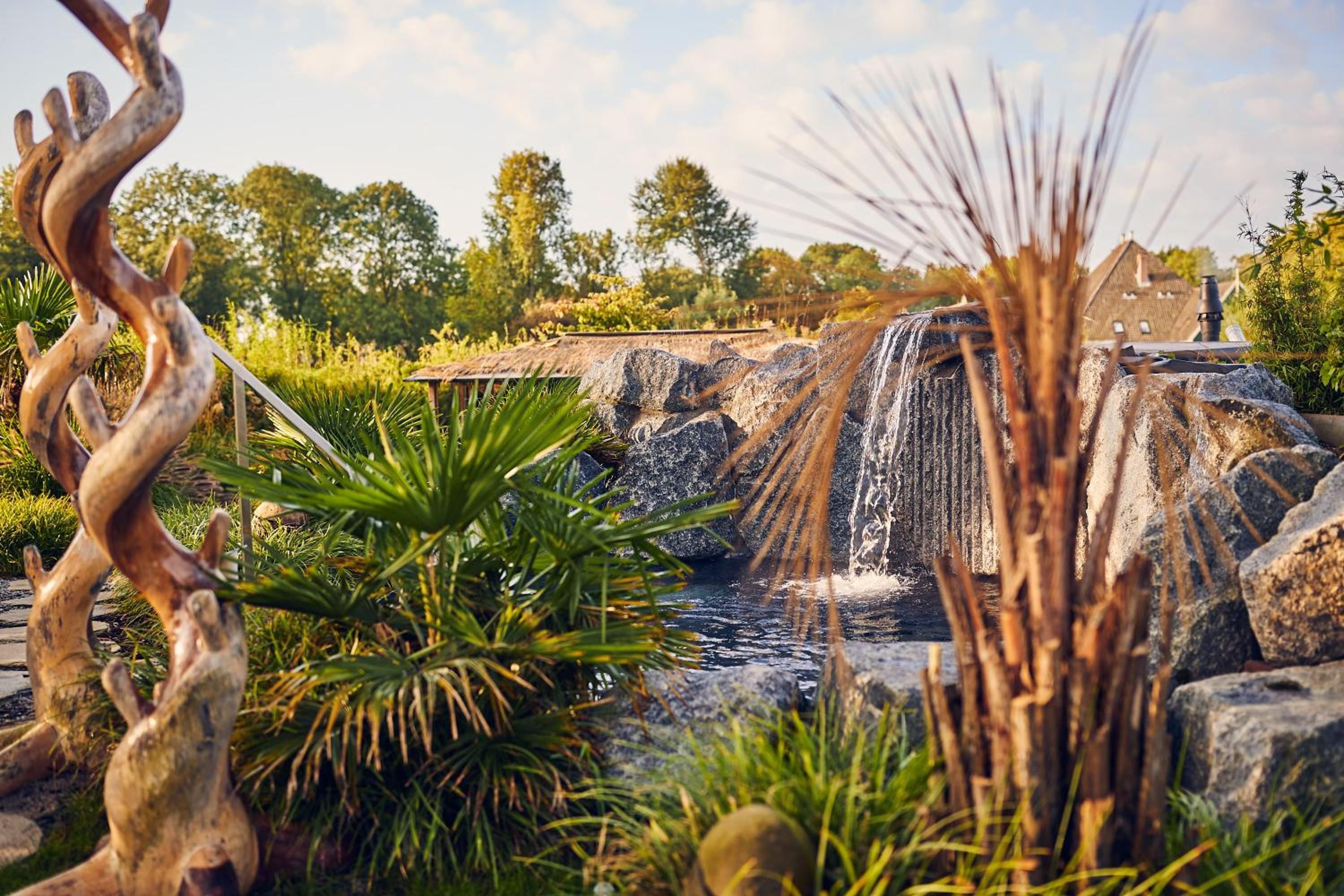 A waterfall feature with surrounding vegetation and a rustic structure.