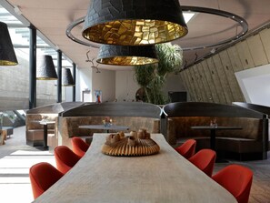 Un interior moderno con una larga mesa, sillas rojas e iluminación colgante original.