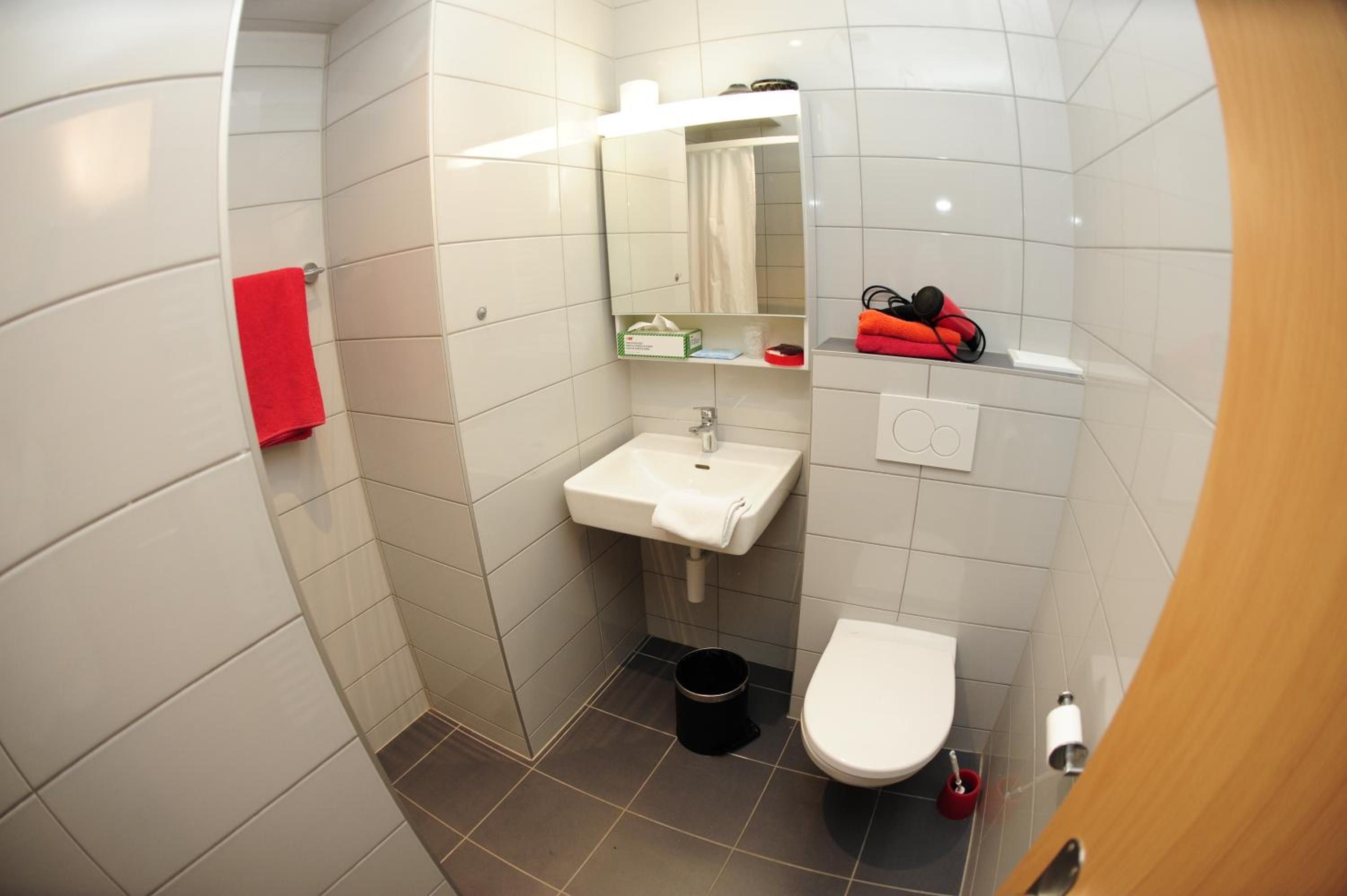 A small bathroom with a white sink, a toilet, and a shower area.